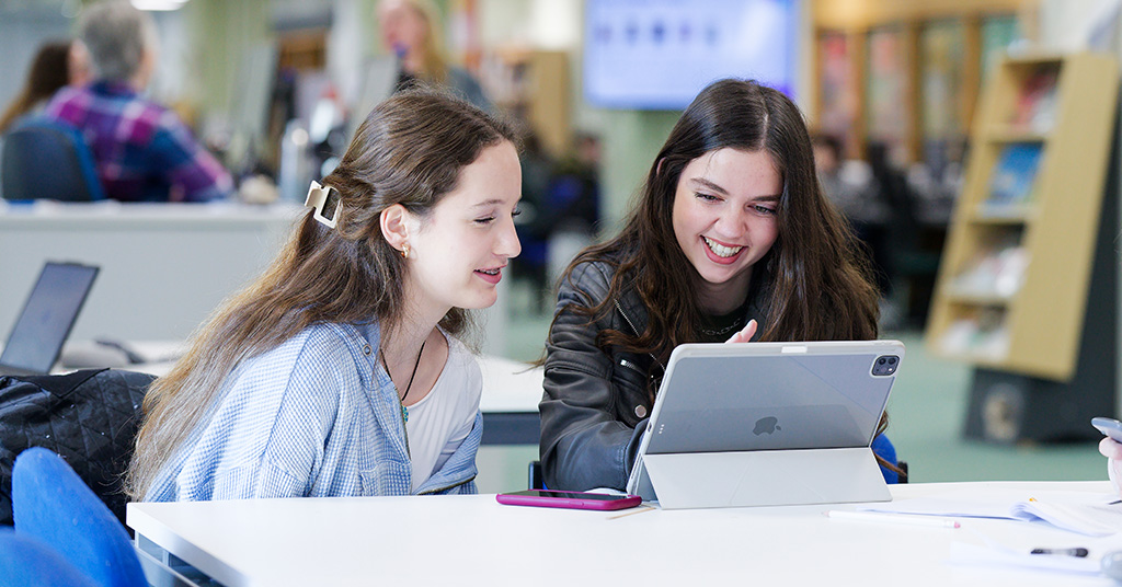 Two students in the library looking at iPad