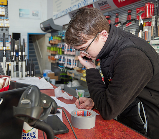 ILS Student answering phone and noting down a message at a DIY store