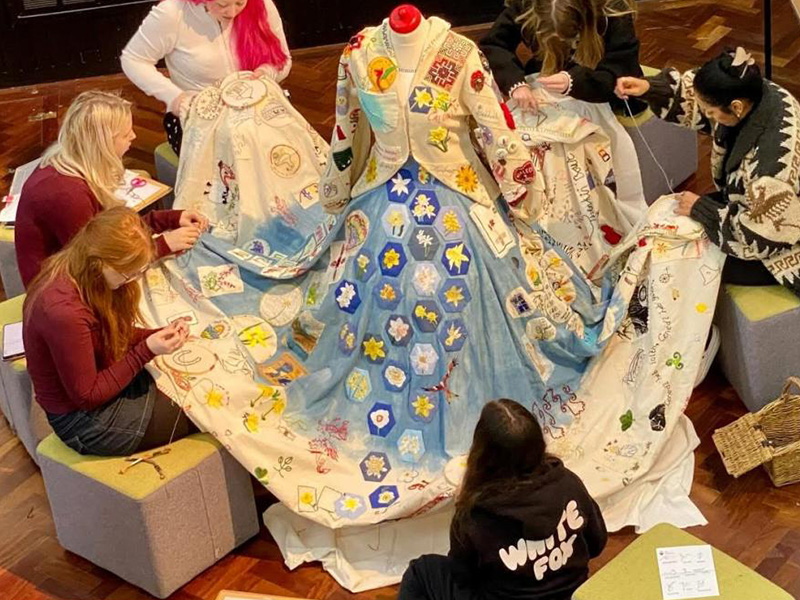 Students working together on a floor length dress