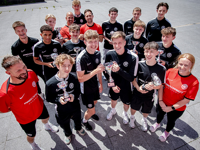 Group picture of Pro:Direct players and staff with trophies