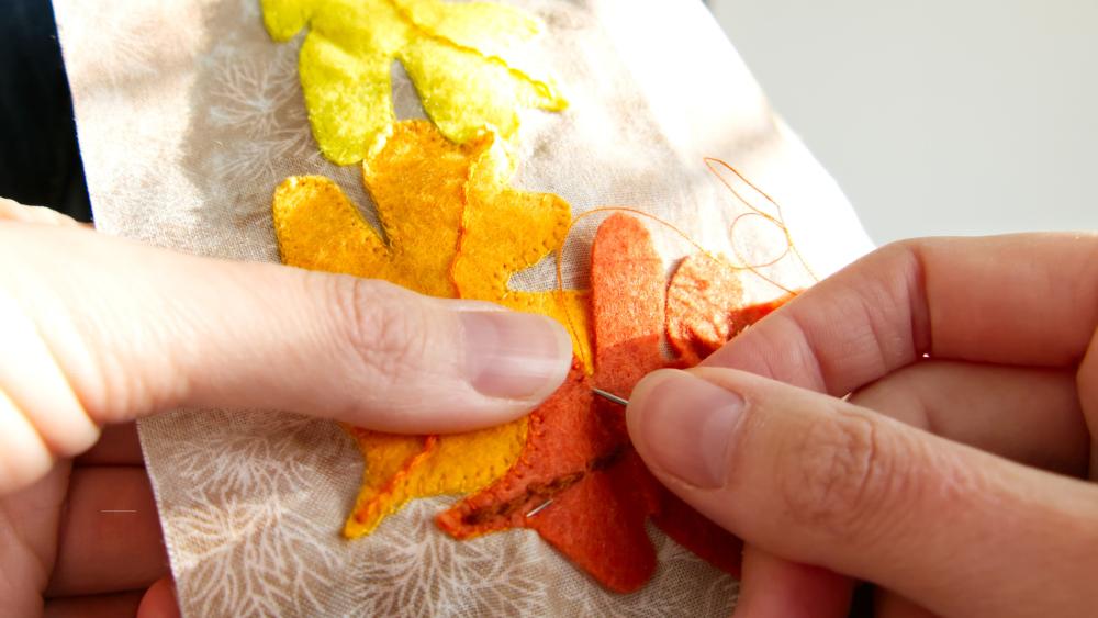 using applique techniques to sew a leaf onto fabric