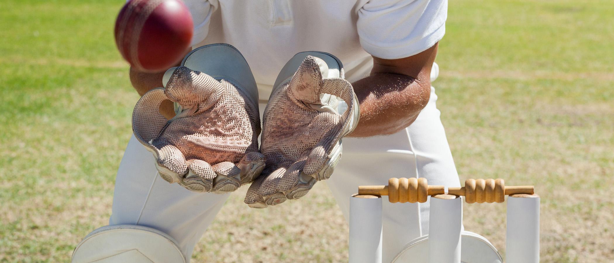 Close up of cricket wicket with someone catching the cricket ball