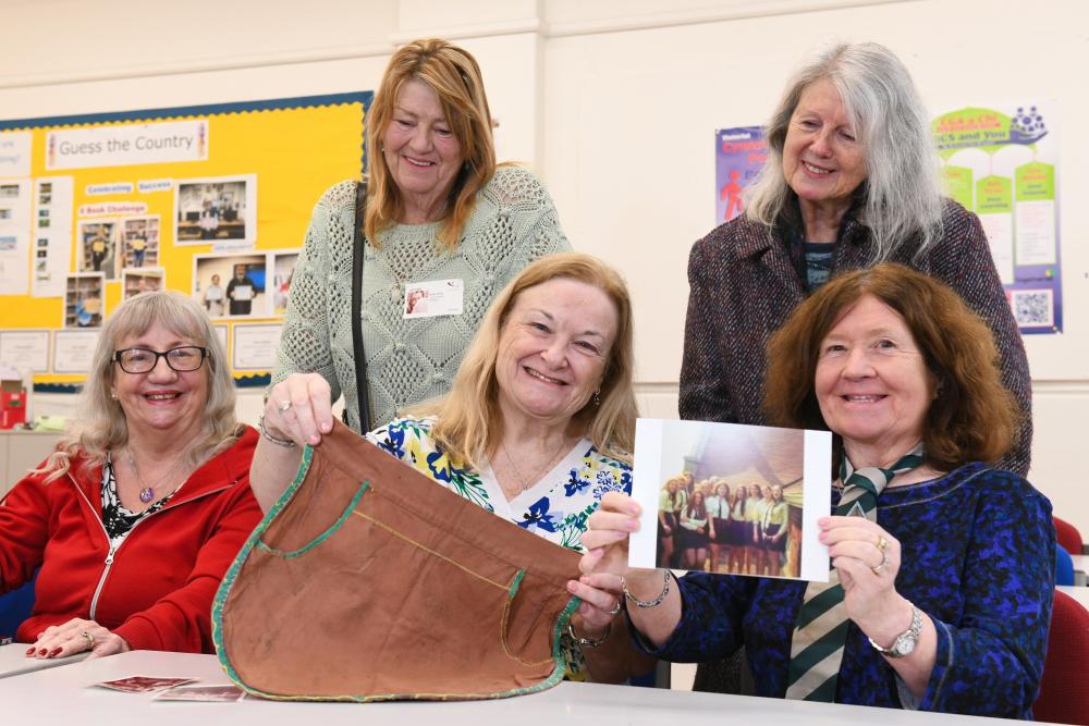 Ladies in classroom, holding up items