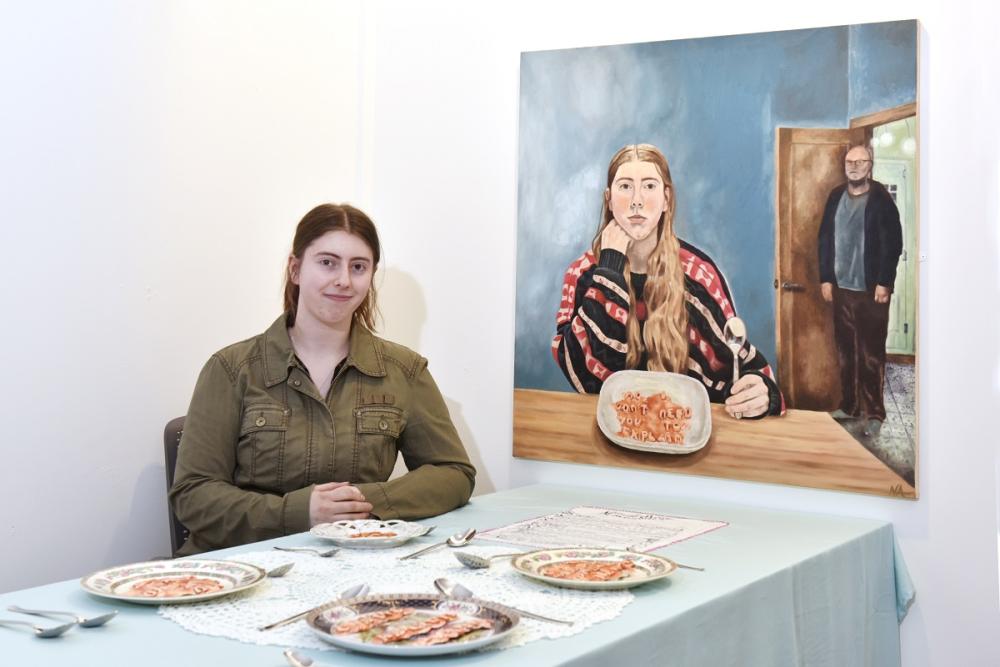Student sitting at table with artwork