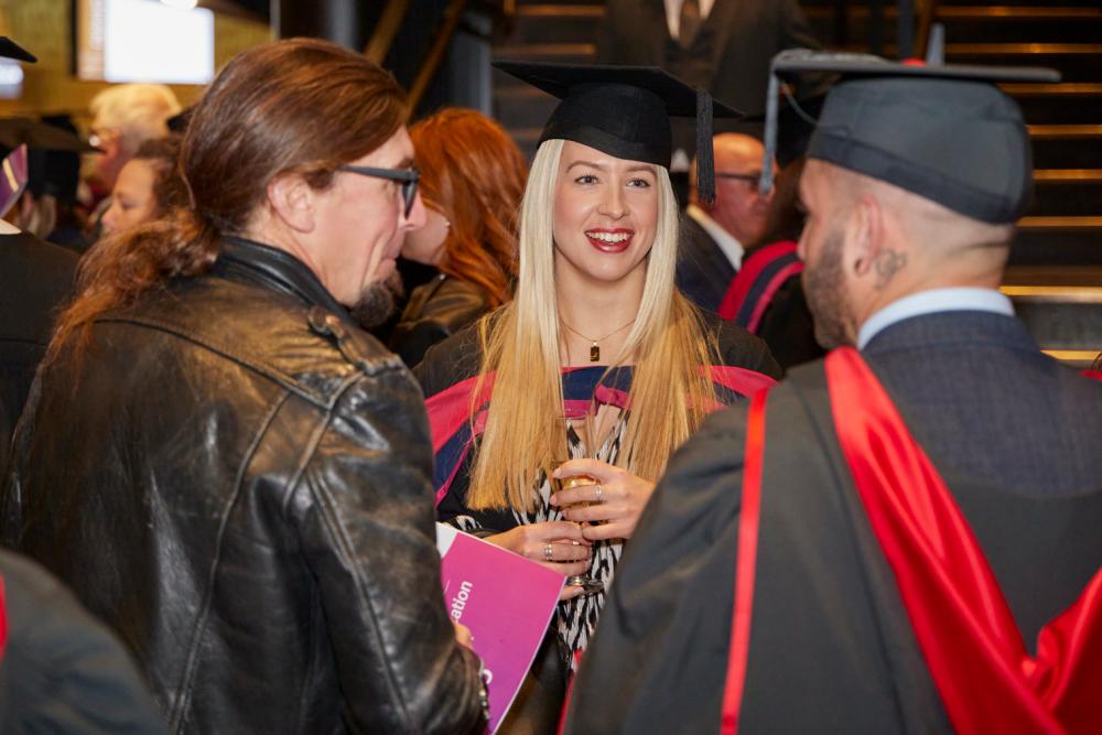 Graduate conversing with other students