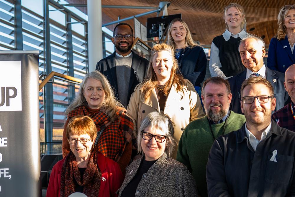 Sarah King and Lorraine Evans with group of people coming together outside the Senedd to mark White Ribbon Day