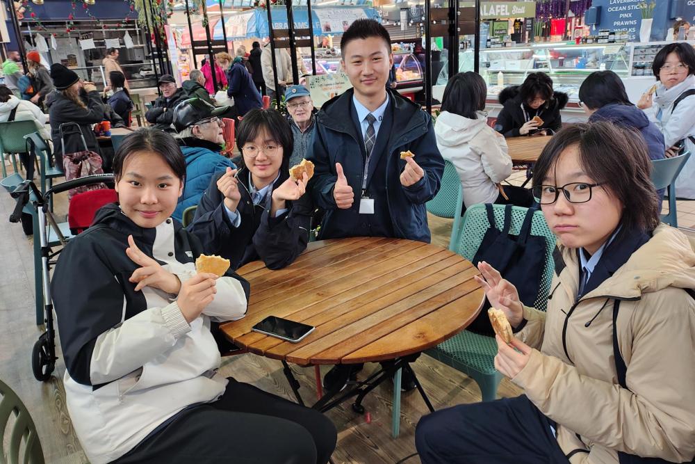 Students at desk smiling at camera