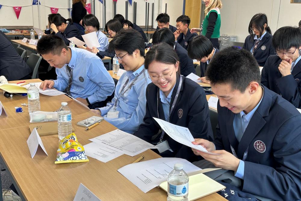 Students at desk reading paper