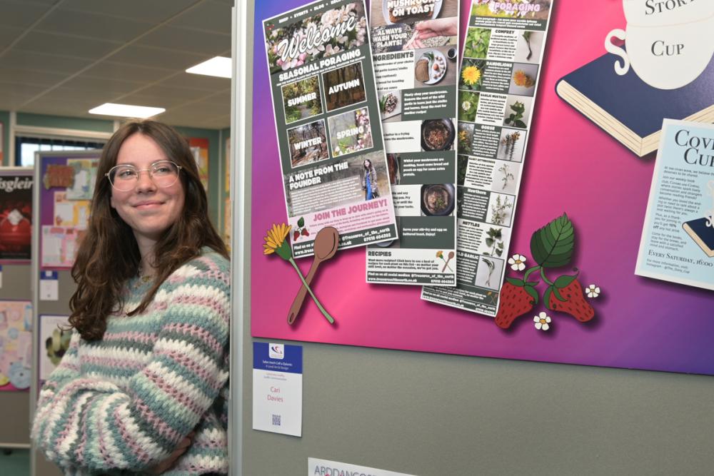 Cari Davies stands next to her graphic design work