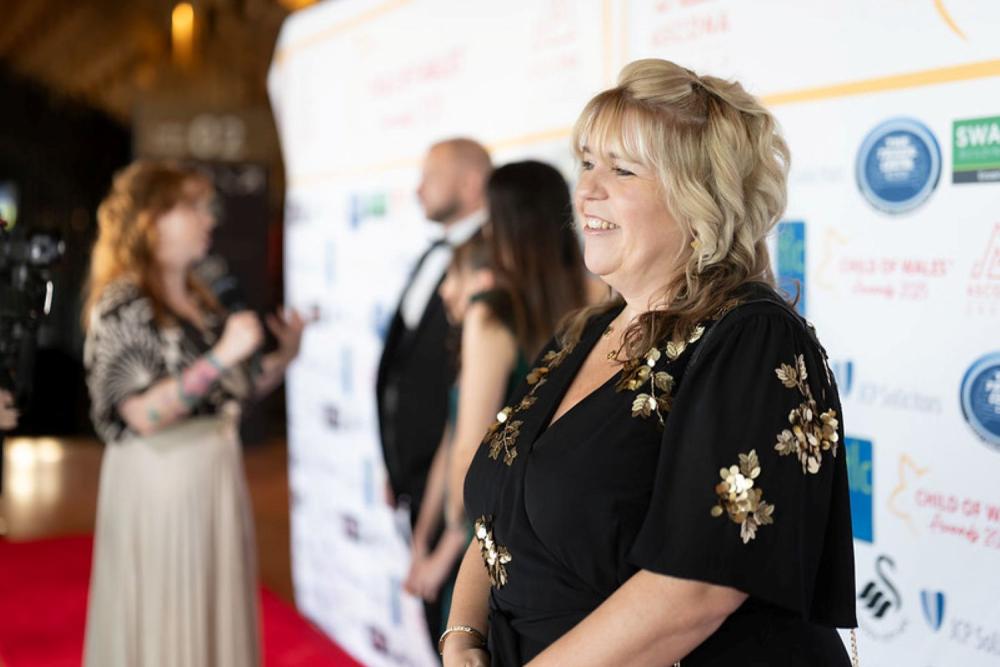 Woman in black and gold dress standing on red carpet at event