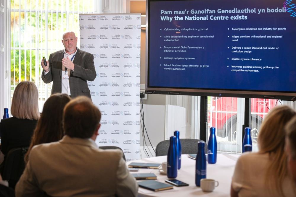 Man in suit giving a presentation, blue screen to right