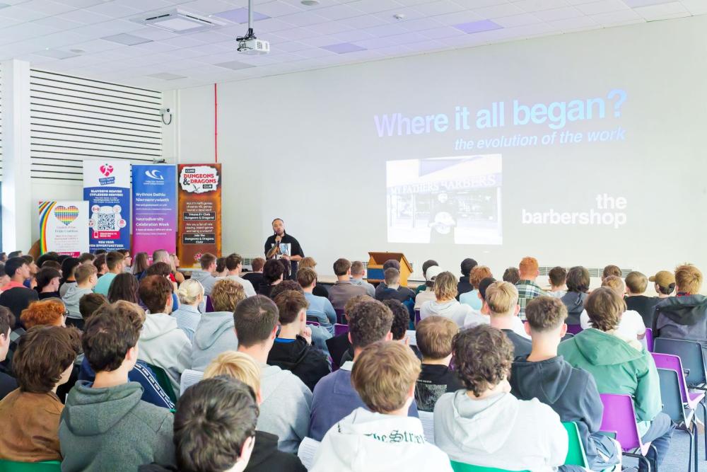 Crowded room, students seated in rows listening to presentation