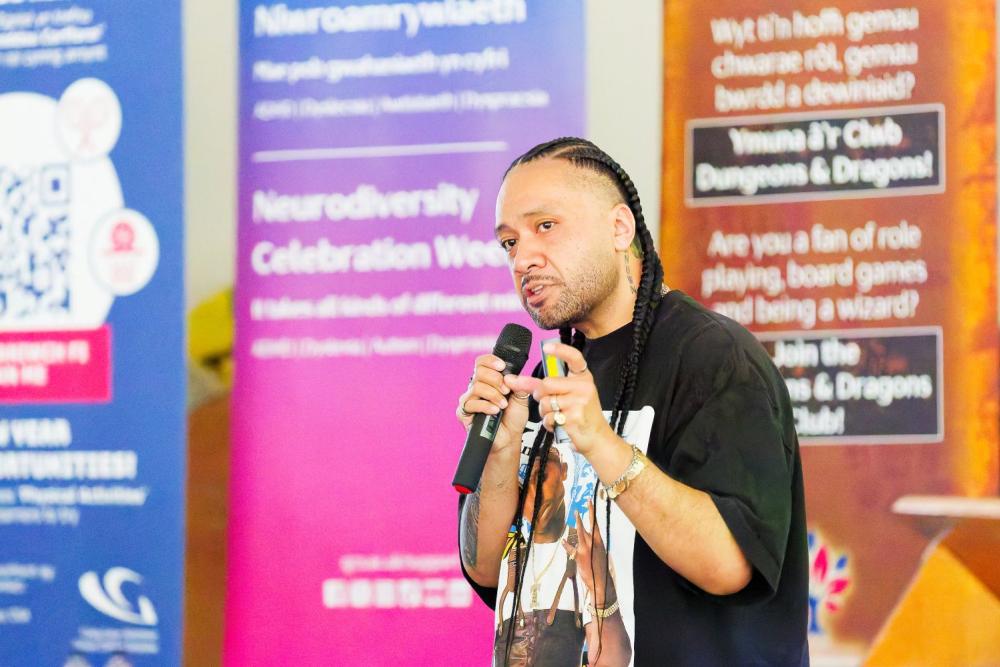 Man in black t-shirt talking into microphone